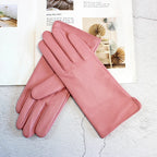 Pair of pink gloves on a textured surface with blurred interior decor background
