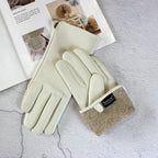 Pair of cream gloves with beige cuffs on a textured surface with a magazine in the background.