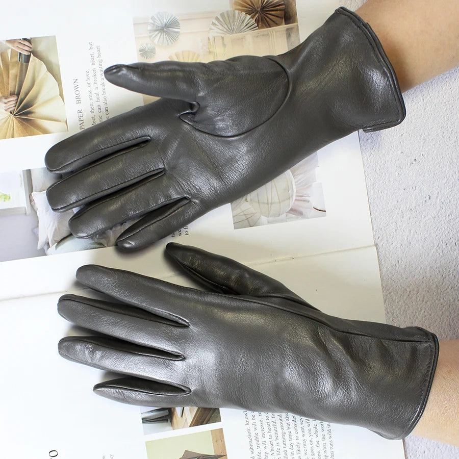 Pair of black leather gloves on a textured surface