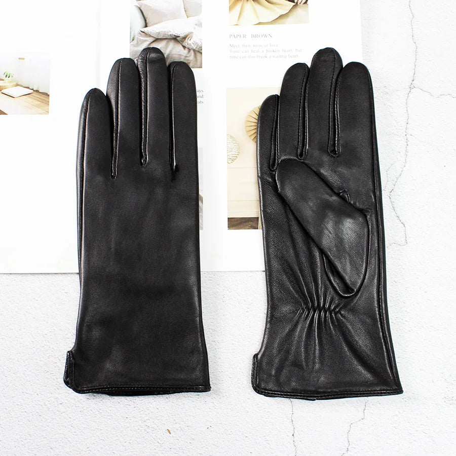 Pair of black leather gloves on a light gray background