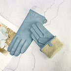 Pair of blue gloves with beige lining on a textured white surface
