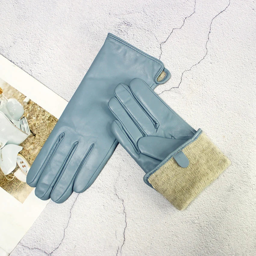 Pair of blue gloves with beige lining on a textured white surface