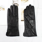 Pair of black leather gloves on a light gray background
