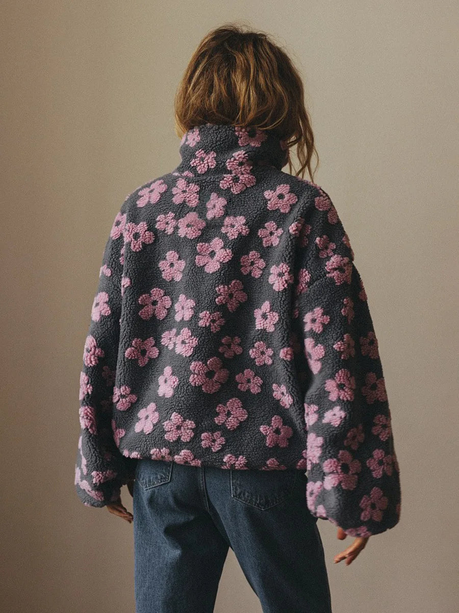 Person wearing a dark gray sweater with pink floral pattern against a plain background