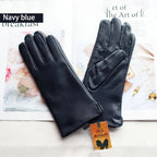 Pair of black leather gloves on a magazine with a visible brand tag.