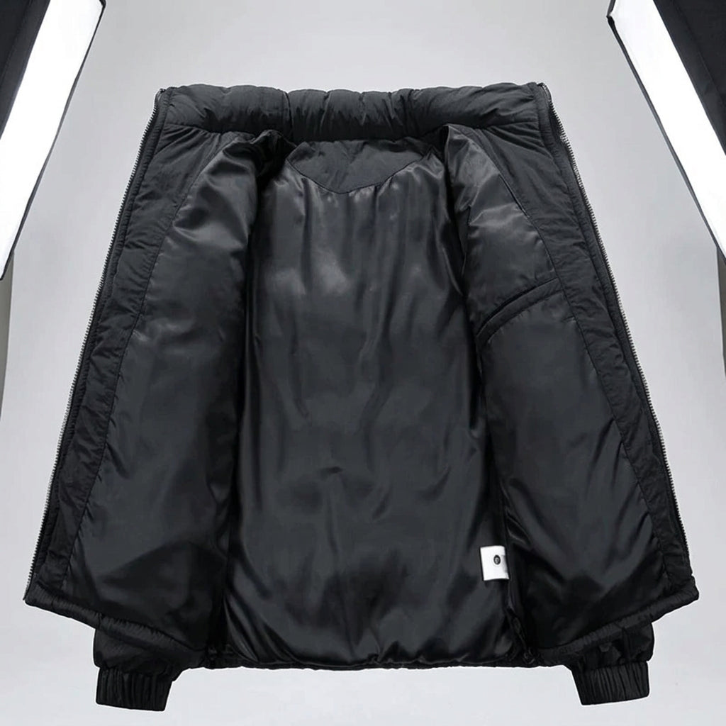Black puffer jacket interior lining shown open against a white background, with elastic cuffs and a small white tag near the lower right side. A small label in the top-left corner reads '変中' in Chinese.