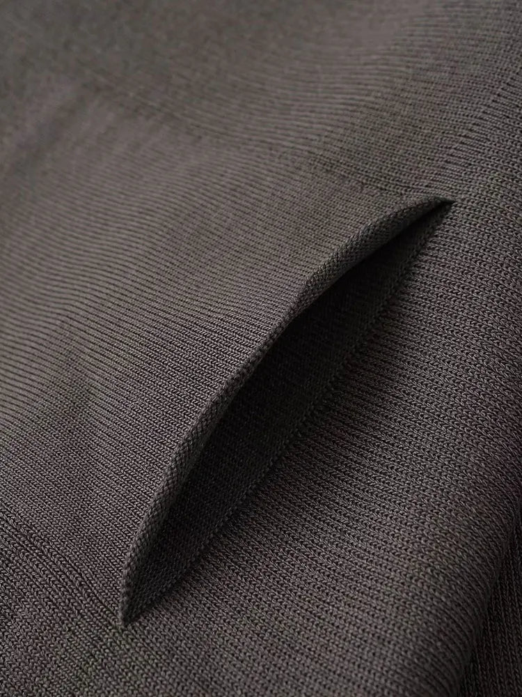 Close-up of a dark charcoal gray textured fabric with a folded corner showing the weave detail.