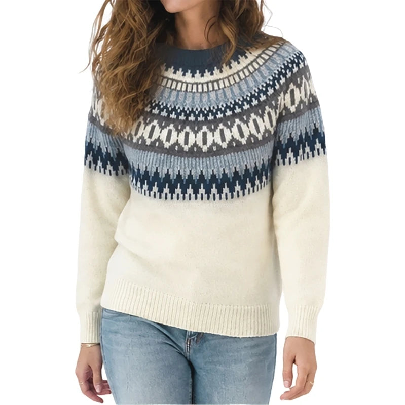 A woman wearing a cream knit sweater with a navy and gray geometric Fair Isle pattern across the yoke, paired with light blue jeans, against a plain white background.