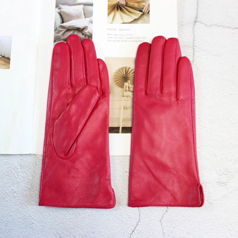 Pair of red leather gloves on a textured surface