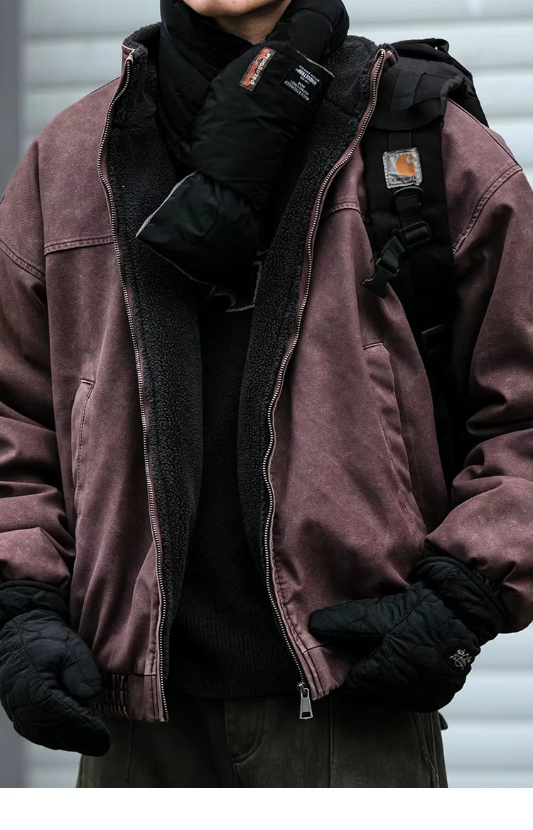 A person wearing a dusty rose work jacket with a black fleece lining, black gloves, and a black backpack, shown from the neck down against a gray background.