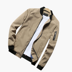 Beige bomber jacket with black trim on a white background