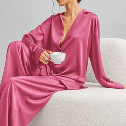 Person wearing a pink satin outfit holding a white cup on a light background