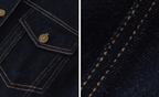 Close-up detail of dark indigo denim fabric showing contrast tan stitching, a pocket flap with a brass-tone button, and a tight fabric texture view.