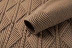 Close-up of a ribbed knit sweater cuff in a warm taupe-brown color, resting on a matching textured knit fabric background.
