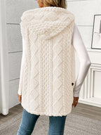 Person wearing a white cable knit vest in a room with a neutral background
