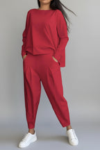 Person wearing a red outfit with white sneakers against a gray concrete background