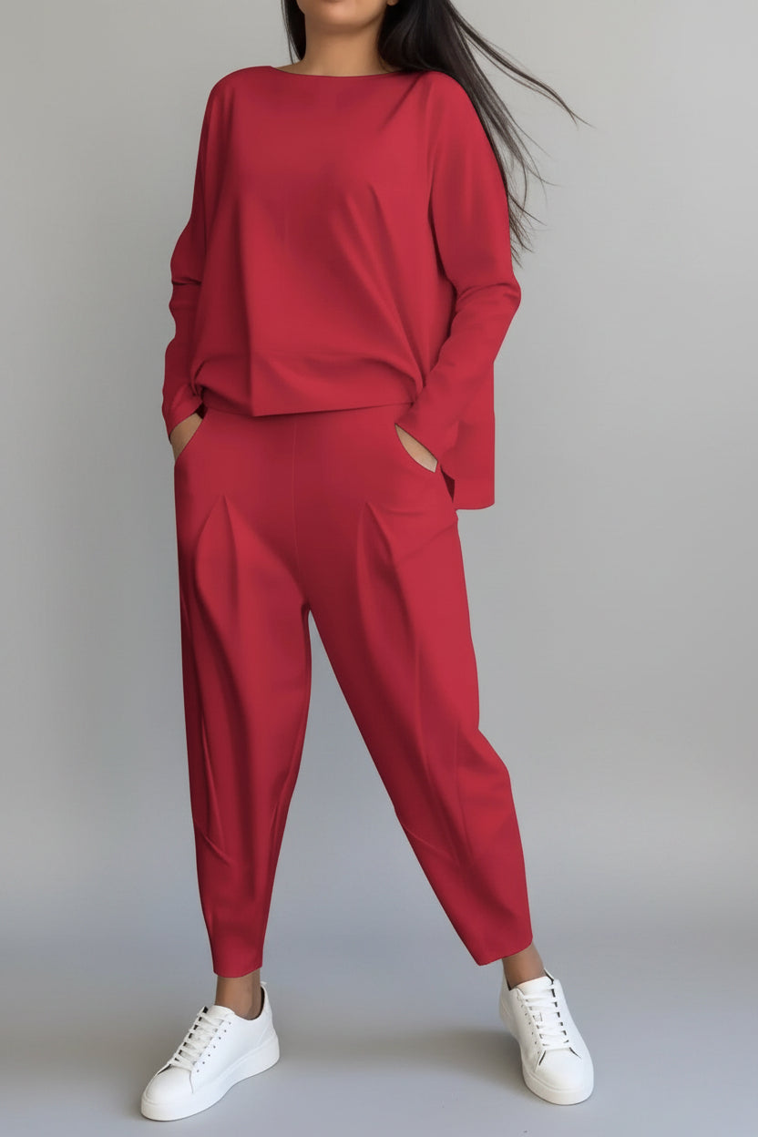 Person wearing a red outfit with white sneakers against a gray concrete background