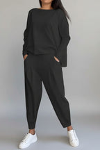 Person wearing a black outfit with white sneakers against a gray concrete background