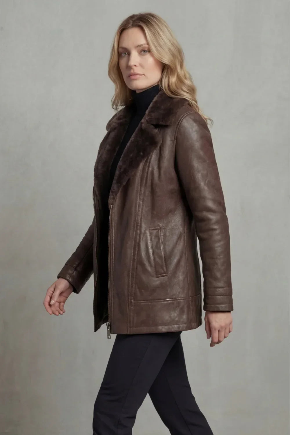 Woman wearing a brown leather coat against a plain background