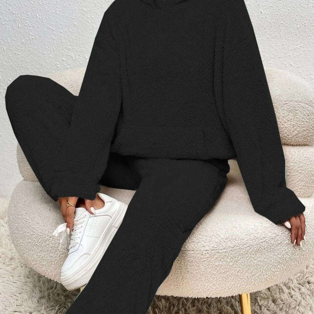 Person wearing a black hoodie and black pants sitting on a white chair.
