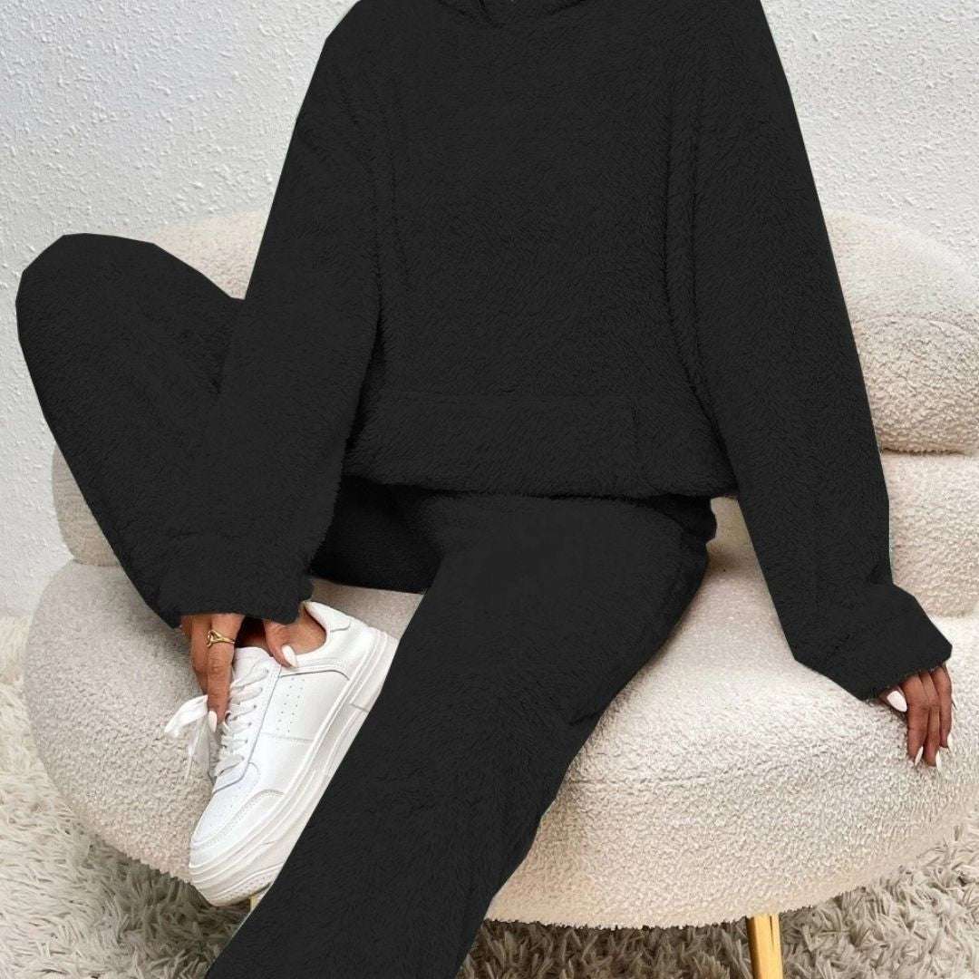 Person wearing a black hoodie and black pants sitting on a white chair.
