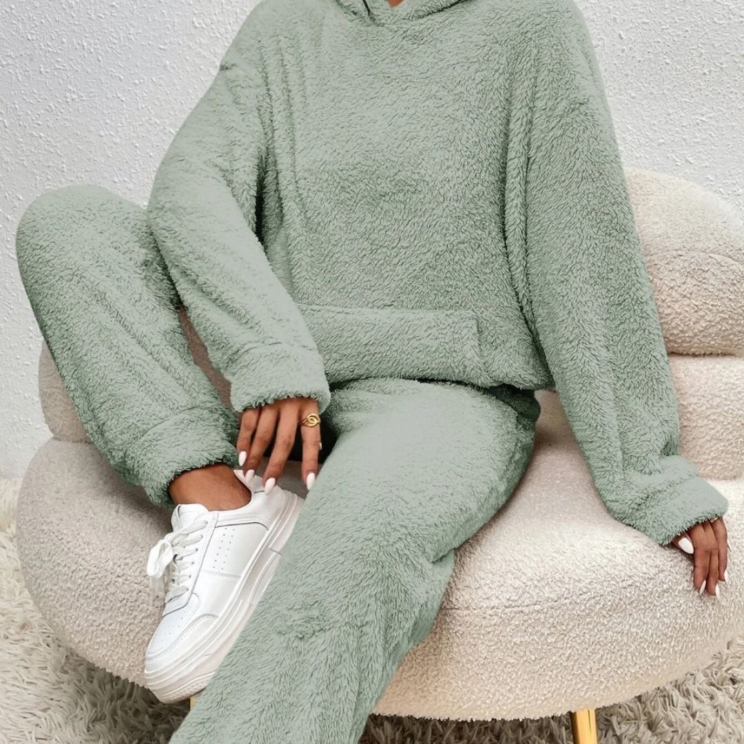 Person wearing a green fleece outfit sitting on a textured chair.