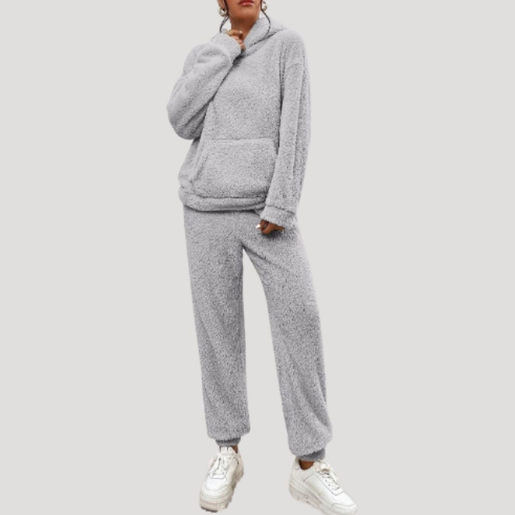 Person wearing a gray fleece hoodie and pants set on a white background
