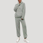 Person wearing a gray fleece tracksuit with white sneakers on a light gray background