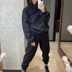 Person wearing a black hoodie and pants in front of a mirror.