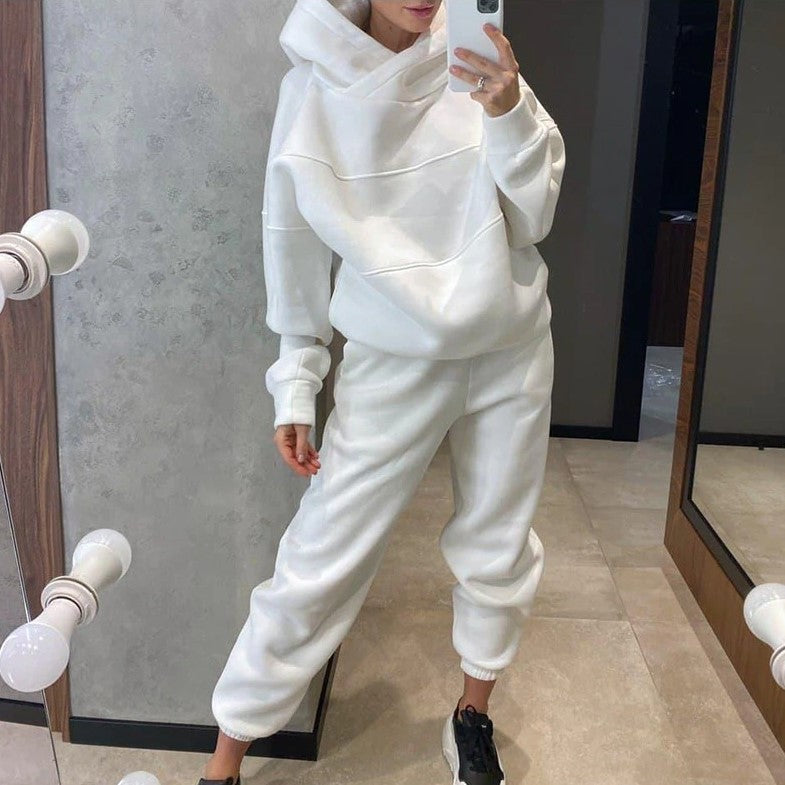 Person wearing a white tracksuit taking a mirror selfie.