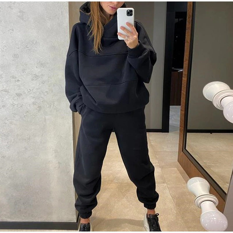 Person wearing a black hoodie and pants standing in front of a mirror.