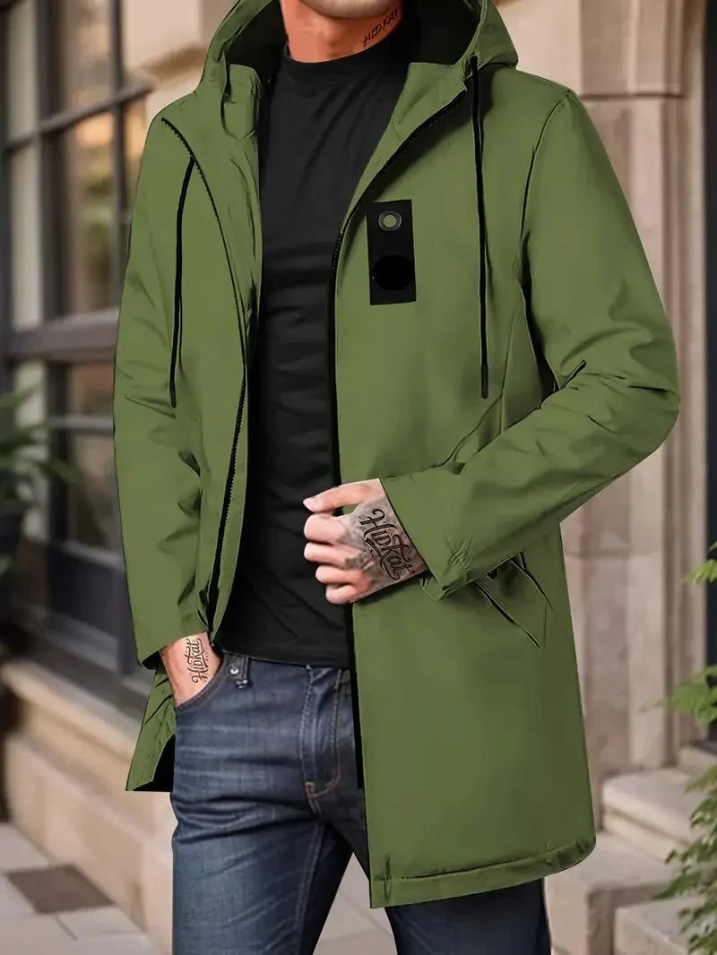 Person wearing a green jacket with a black shirt and jeans, standing outdoors.