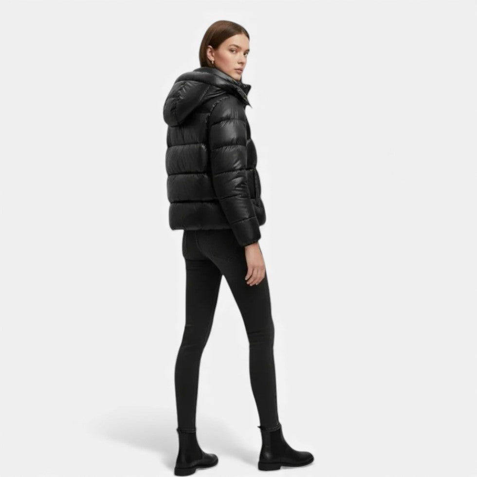 Person wearing a black puffer jacket and pants on a white background