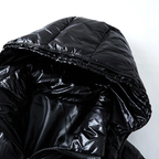 Close-up of a black puffer jacket with shiny surface on a white background