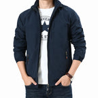 A man wearing a navy blue hooded zip-up jacket over a white graphic t-shirt and dark blue jeans, shown from the neck down against a plain white background.