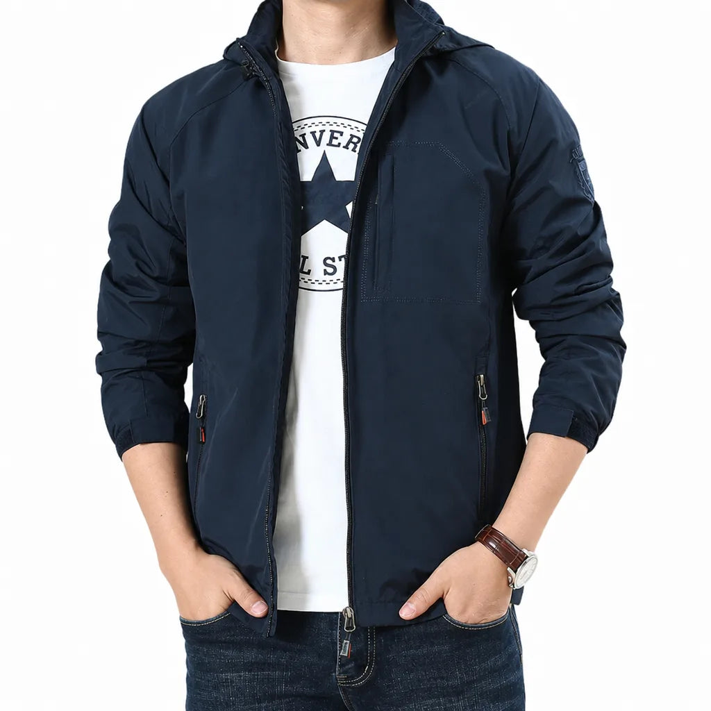 A man wearing a navy blue hooded zip-up jacket over a white graphic t-shirt and dark blue jeans, shown from the neck down against a plain white background.