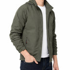 An olive green lightweight hooded jacket worn by a model over a white t-shirt and dark blue jeans, shown against a plain white background.